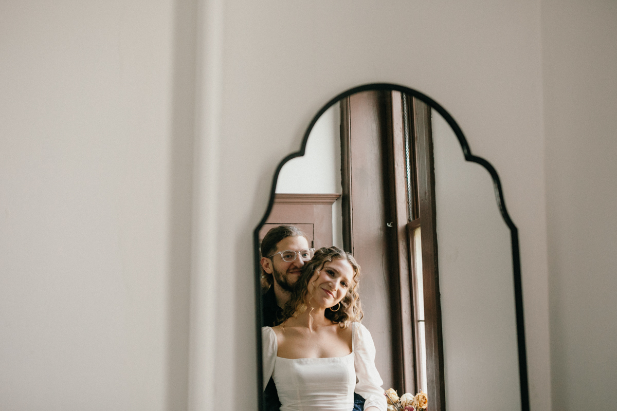 Home engagement session with couple framed in hallway mirror
