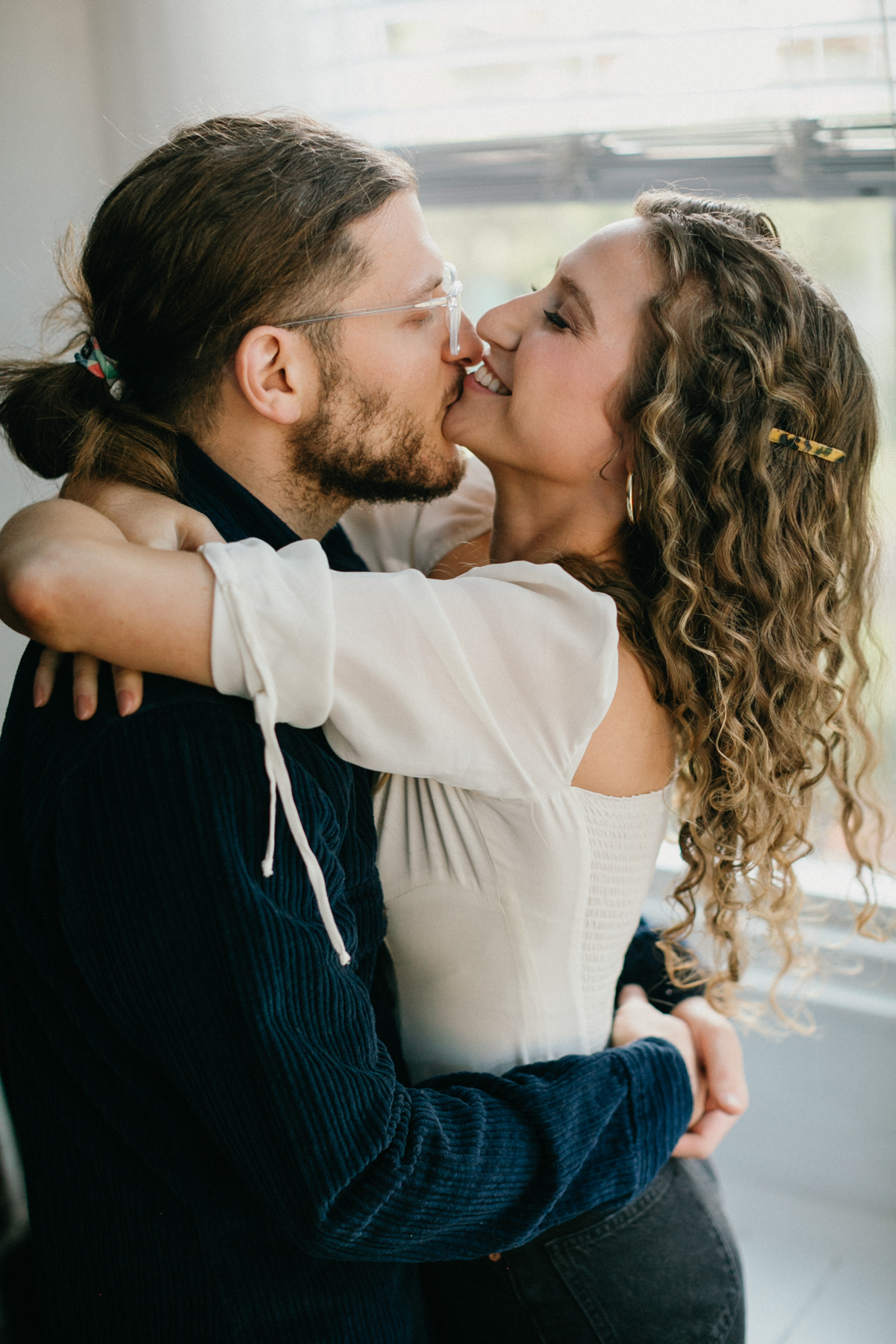 Clean and timeless home engagement photo of couple in natural window light