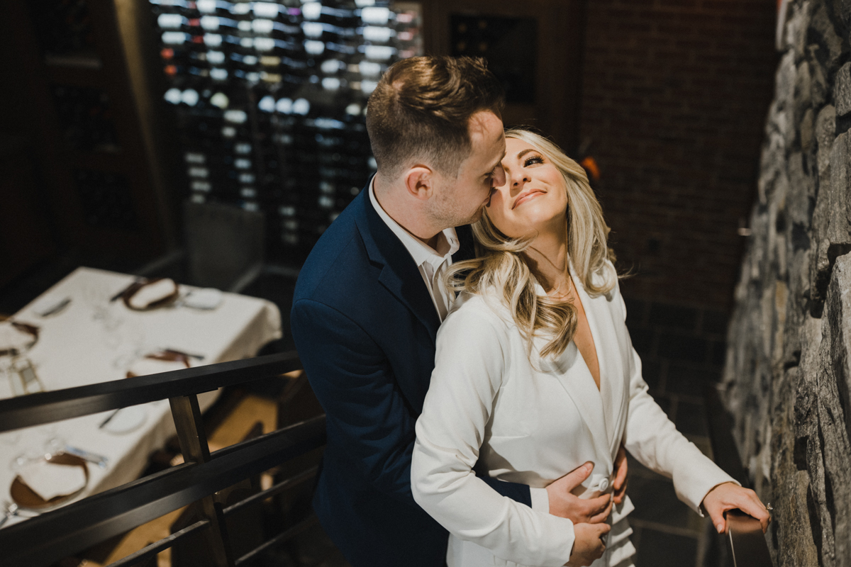 Stolen kiss in corner café during indoor Philly engagement shoot