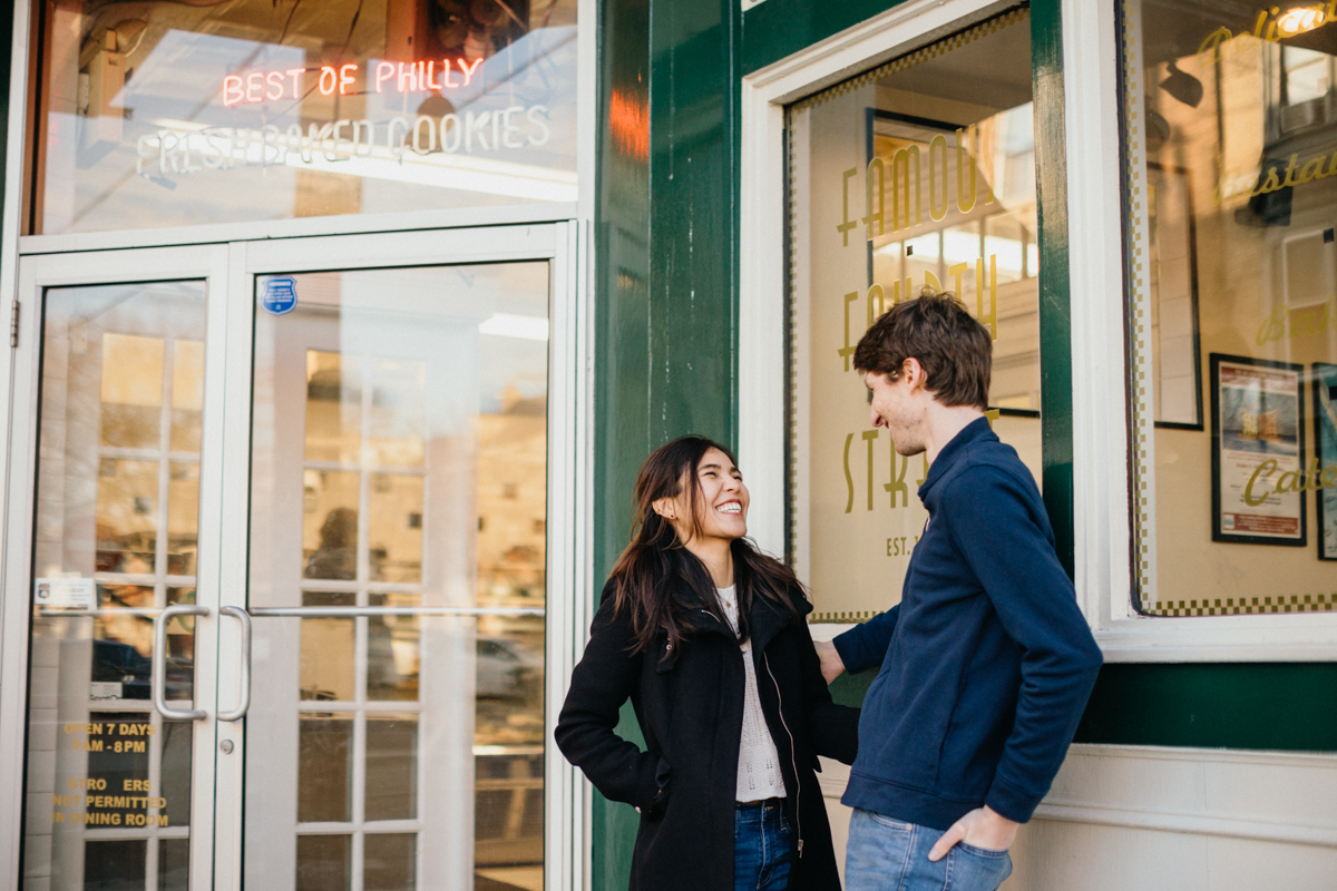 Close-up engagement portrait with 4th Street Deli sign in Queen Village