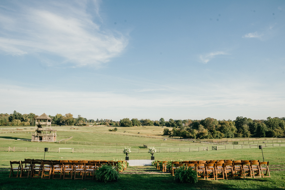 Ceremony on the lawn at Radnor Hunt with horses in the distance