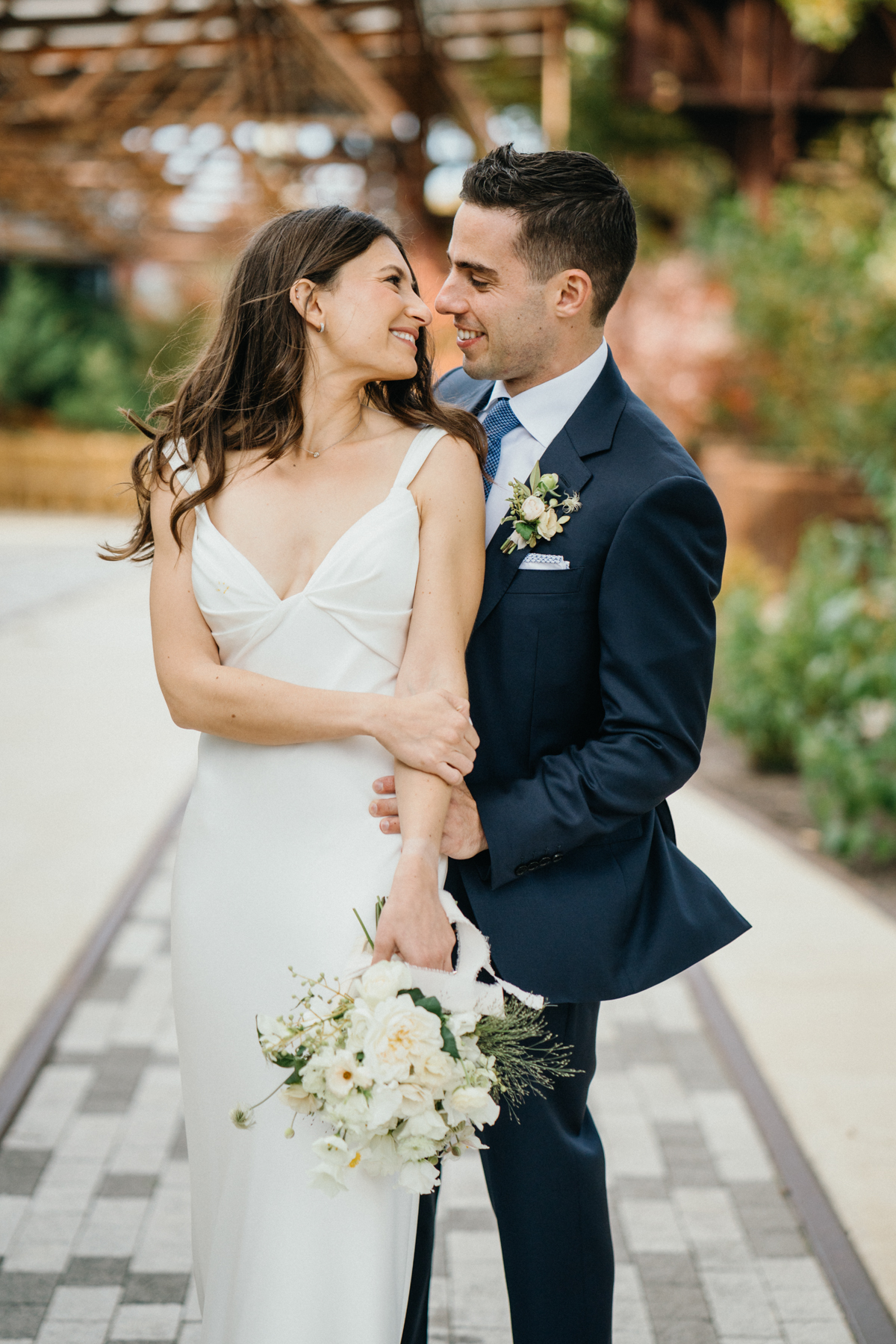 Bride and groom holding hands beneath exposed beams at The Pumphouse at Ironworks