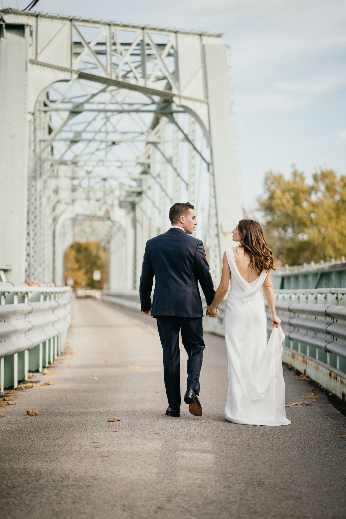 Bride and groom walking across bridge at Ironworks at Pencoyd Landing