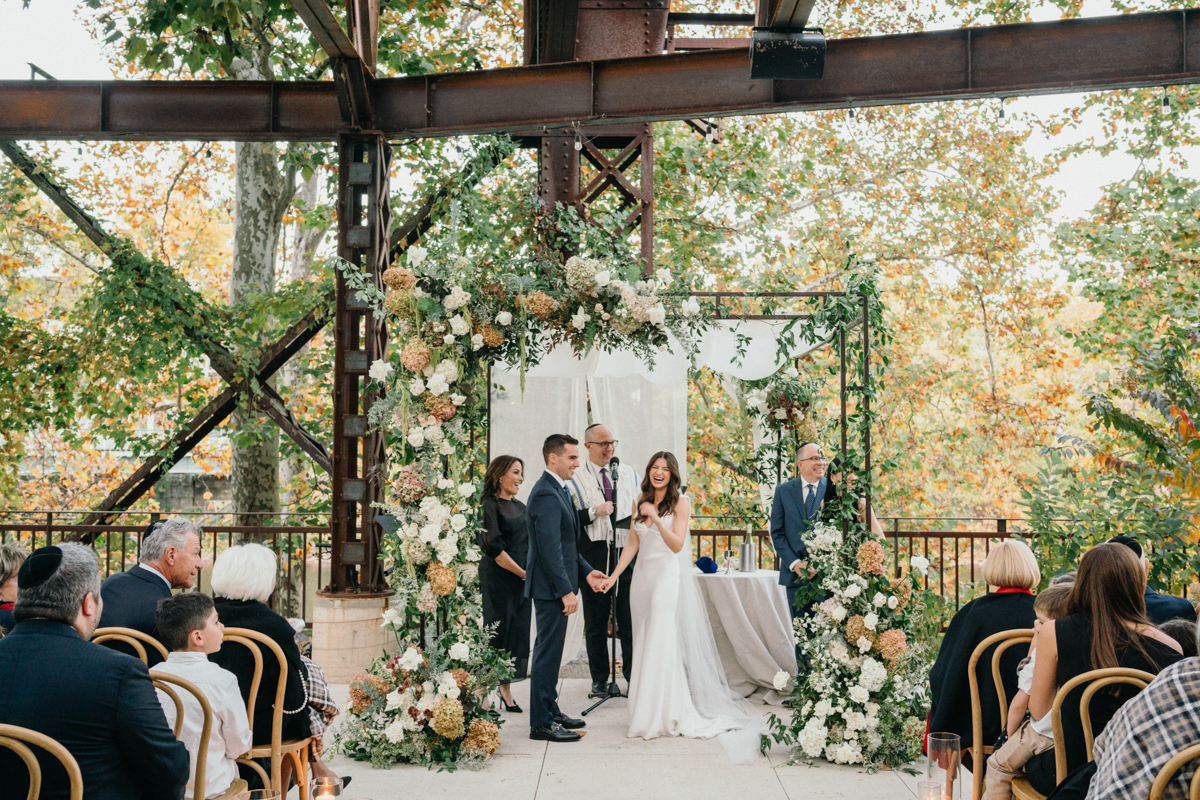 Bride and groom under floral arch at Pencoyd Landing