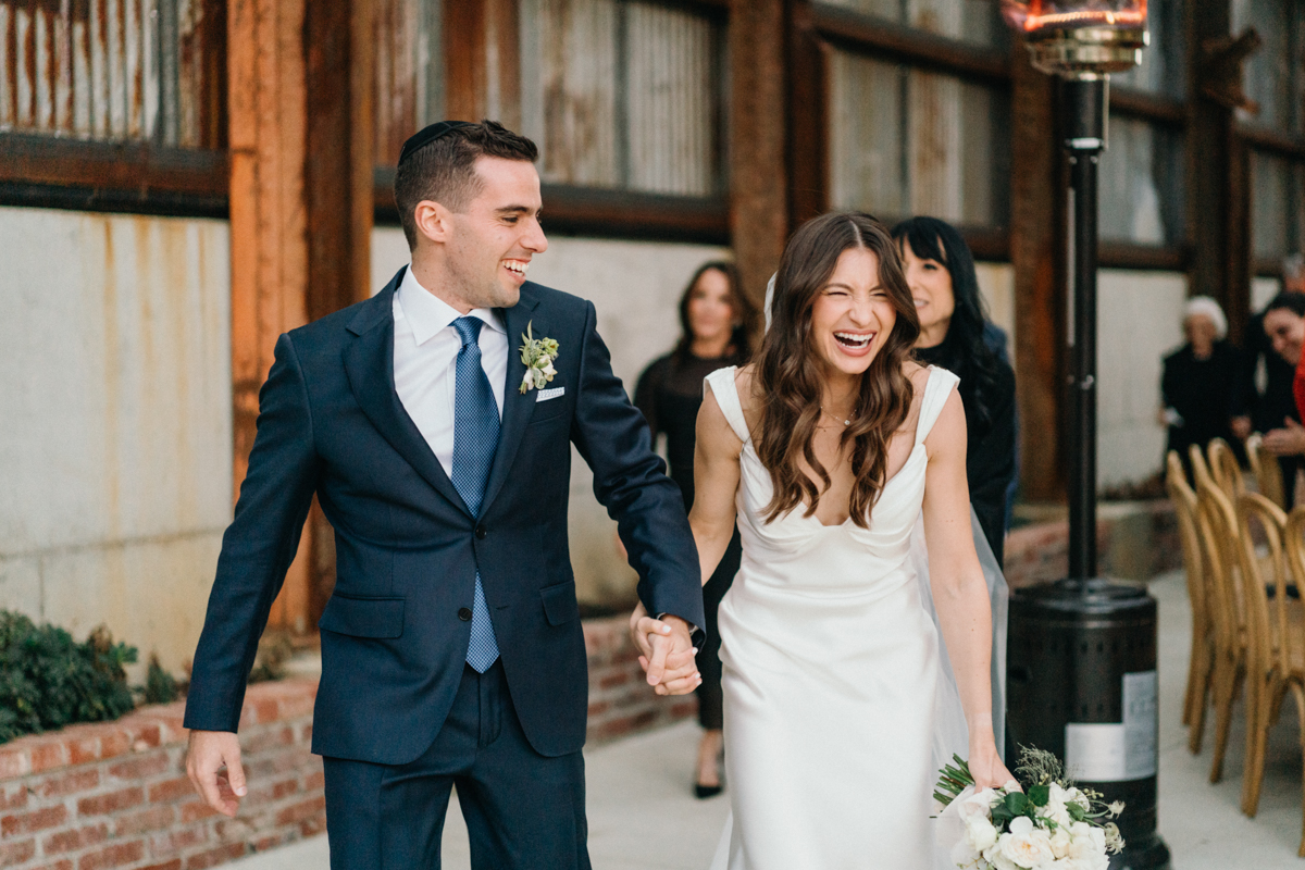 Candid smiles during ceremony exit at Train Shed